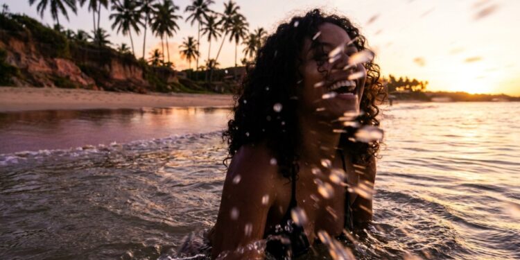 A vila baiana onde os coqueiros formam e a praia espelhada cria fotos perfeitas ao pôr do sol