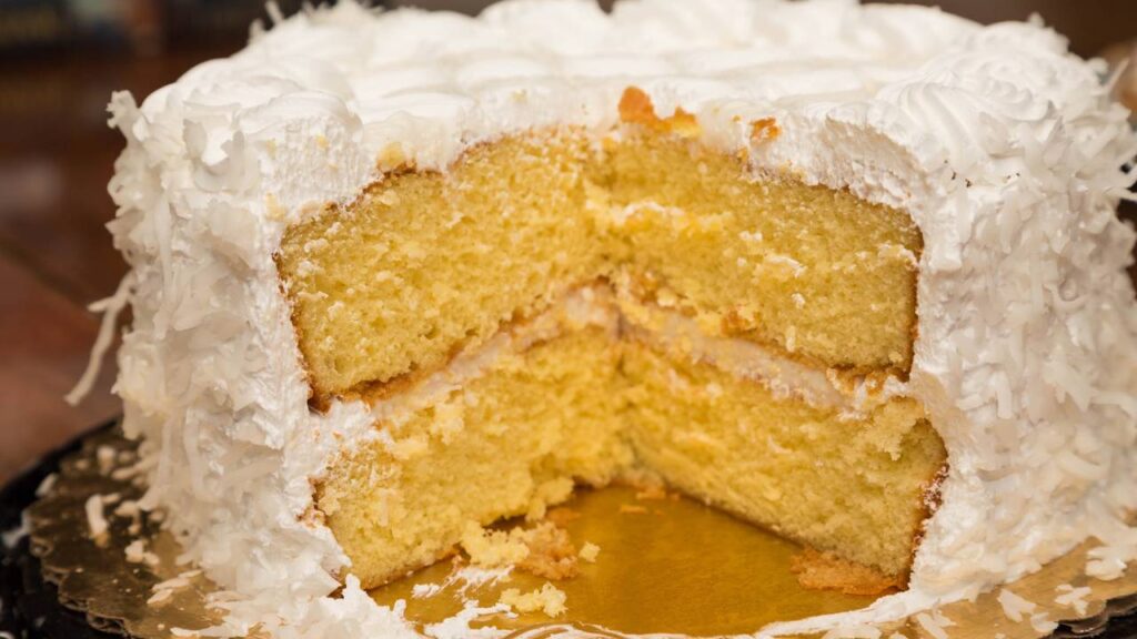 Esse bolo de Ano Novo com coco, frutas e cobertura branca representa prosperidade, paz e renovação na ceia