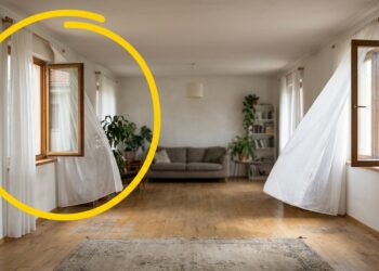 Janela residencial aberta com cortina leve balançando ao vento em ambiente iluminado por luz natural.