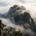 Pico de montanha japonesa firme e imponente cercado por densa neblina matinal sob a luz do amanhecer.