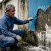 Pintor profissional inspecionando tinta acrílica descascando e massa esfarelada em parede externa de reboco novo