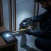 Encanador instalando registro motorizado inteligente em tubulação de água com celular mostrando alerta de vazamento