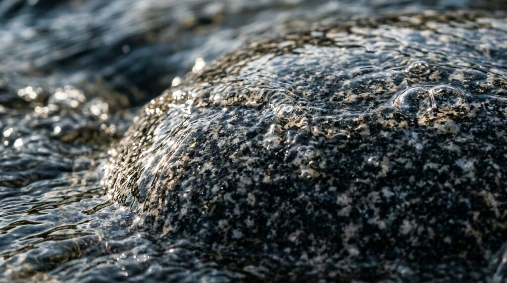 Detalhe em macro de água límpida escorrendo e polindo uma pedra de rio arredondada