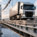 Caminhão pesado atravessa uma ponte de concreto projetada para apresentar pequenas deformações sob as cargas do tráfego.