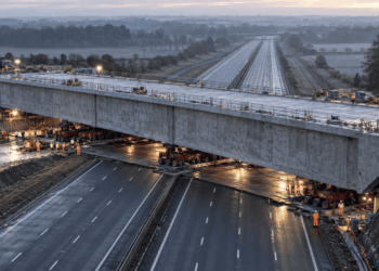 Viaduto gigante de concreto armado sendo empurrado por macacos hidráulicos sobre trilhos lubrificados na autoestrada M42