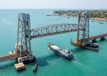 Vão ferroviário da Ponte Pamban elevado enquanto navio passa por baixo.