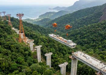 Equipamento de construção viaja suspenso por cabos acima da floresta.