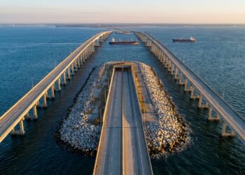 Vista aérea do Chesapeake Bay Bridge-Tunnel mostrando viadutos de concreto sobre o mar entrando em ilha artificial com portal para túnel submarino