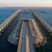Vista aérea do Chesapeake Bay Bridge-Tunnel mostrando viadutos de concreto sobre o mar entrando em ilha artificial com portal para túnel submarino