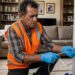 Pedreiro com luvas de proteção aplicando resina sob pressão com mangueira de injeção em trinca de parede residencial.