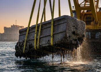 Bloco monumental de granito de 80 toneladas içado por guindaste marítimo das águas de Alexandria com cintas de sustentação