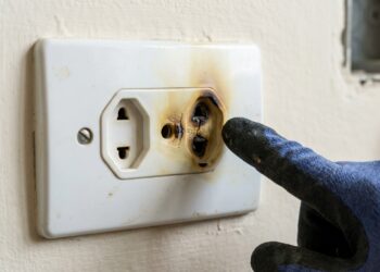 Tomada apresenta plástico amarelado e deformação provocada por aquecimento na região dos contatos.
