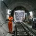 Corte subterrâneo mostra uma grande tuneladora passando poucos metros abaixo de um túnel de metrô existente.