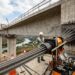 Macaco hidráulico tensiona cordoalhas de aço instaladas dentro de uma viga de concreto de uma ponte.