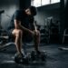Praticante de musculação sentado em um banco de academia com expressão cansada e reflexiva após o treino