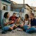 Jovens conversam presencialmente em um bairro brasileiro no fim dos anos 1990 sem celulares por perto.