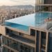 Pessoas utilizam uma grande piscina de borda infinita construída na cobertura de um edifício.