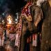 Elefanta idosa vestida com túnica cerimonial decorada com luzes e bordados durante procissão noturna em rua do Sri Lanka