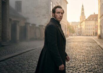 Søren Kierkegaard olha para trás enquanto segue por uma rua de Copenhague.