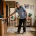 Homem com mais de 60 anos caminha com passos cautelosos e procura apoio próximo.