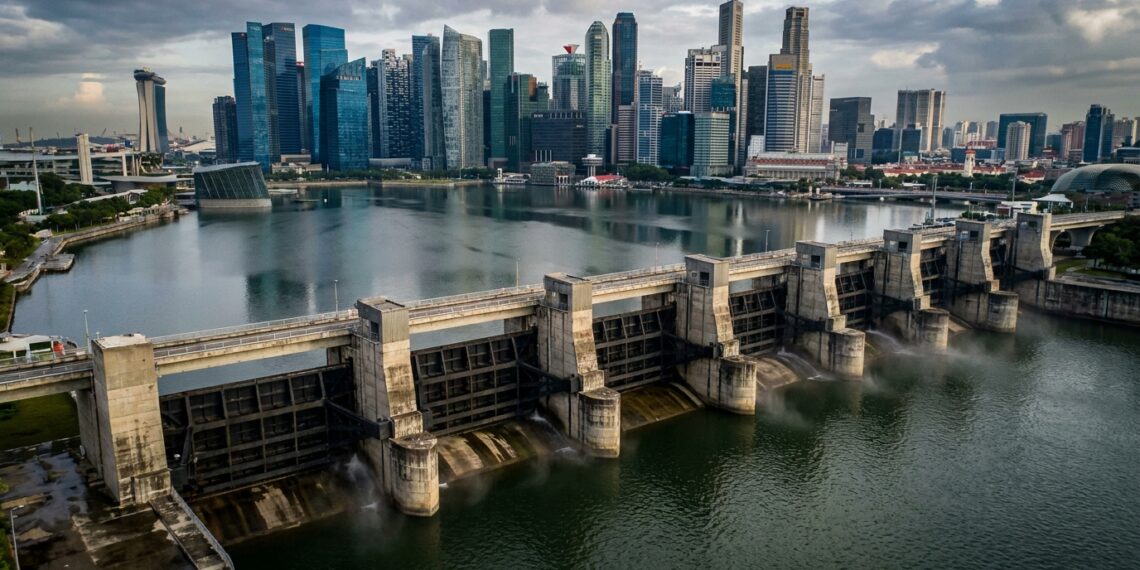 Comportas de aço da Marina Barrage fechando o canal estuarino com o reservatório de água doce e arranha-céus de Singapura ao fundo