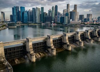 Comportas de aço da Marina Barrage fechando o canal estuarino com o reservatório de água doce e arranha-céus de Singapura ao fundo