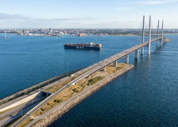 Vista aérea panorâmica da ligação de Øresund mostrando a ponte estaiada descendo na ilha artificial de Peberholm e mergulhando no túnel submarino.
