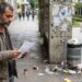 Pessoa segura papel diante de espaço público com sinais de desordem.