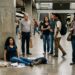 Passageiros percebem uma pessoa que precisa de ajuda enquanto observam a reação das outras testemunhas.