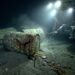 Barris de lixo nuclear oxidados e rompidos repousando no sedimento do leito marinho abissal a quase 5 mil metros de profundidade sob a luz de submersível