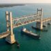 Vão ferroviário da Nova Ponte Pamban elevado entre duas torres enquanto uma embarcação passa pelo canal abaixo.