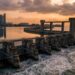Vista aérea da barreira de 350 metros e nove comportas da Marina Barrage represando o reservatório com arranha-céus de Singapura ao fundo.