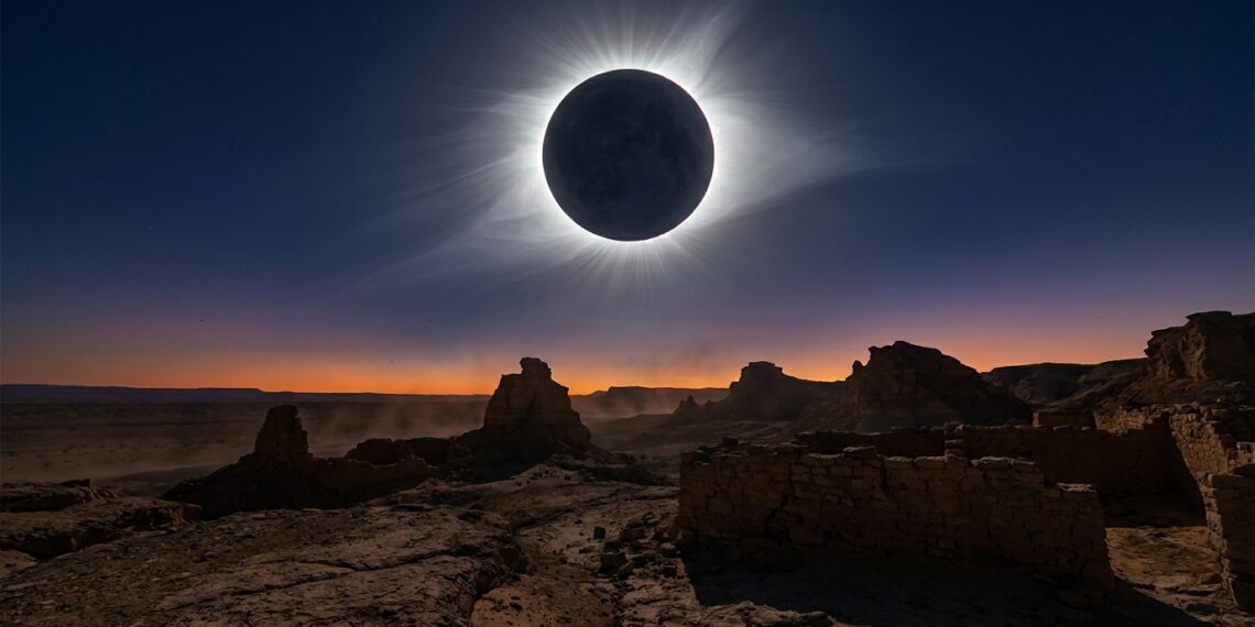 Silhueta ampliada da Lua cobrindo totalmente o disco do Sol e projetando a coroa solar prateada sobre horizonte desértico