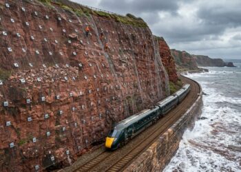 Falésia coberta por extensa rede de aço presa por ancoragens acima dos trilhos da ferrovia de Dawlish.