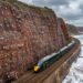 Falésia coberta por extensa rede de aço presa por ancoragens acima dos trilhos da ferrovia de Dawlish.