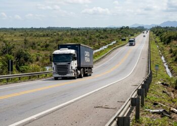Caminhão passa por trecho de rodovia com depressão gradual no pavimento, mas sem buracos.