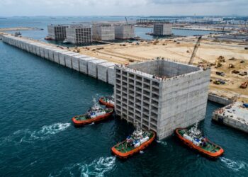 Caixão gigante de concreto é transportado pelo mar para formar o paredão do Tuas Port.