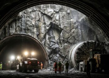 Galeria subterrânea do Túnel de Base de São Gotardo com arcos de sustentação e iluminação industrial sob maciço rochoso alpino