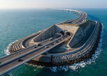 Viaduto rodoviário descendo sobre ilha artificial em mar aberto e entrando no portal do túnel submarino da travessia Hong Kong-Zhuhai-Macau.