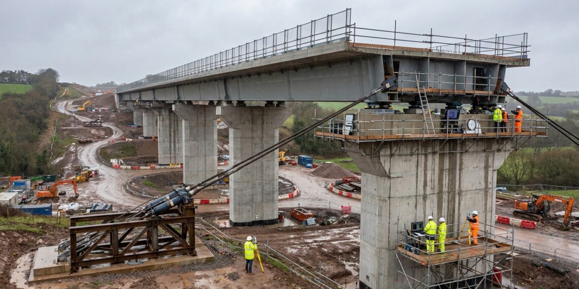 Sistema hidráulico puxa enorme viaduto sobre apoios deslizantes.