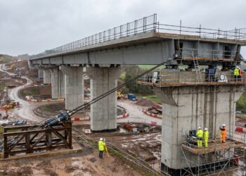 Sistema hidráulico puxa enorme viaduto sobre apoios deslizantes.