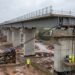 Sistema hidráulico puxa enorme viaduto sobre apoios deslizantes.