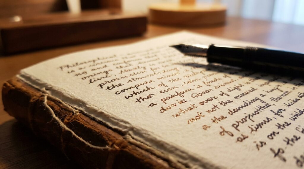 Páginas abertas de um caderno antigo com anotações manuscritas e uma caneta-tinteiro clássica apoiada sobre a folha.