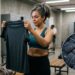 Mulher segura roupa de academia já usada enquanto detalhe ampliado representa resíduos invisíveis retidos nas fibras do tecido.
