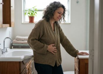 Mulher segura o abdômen enquanto sente desconforto relacionado à constipação.
