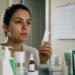 Mulher observa a acne no espelho poucos dias após iniciar um produto para tratamento da pele.