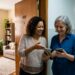 Mulher conversa com vizinho enquanto ajuda a conectar um celular à rede Wi-Fi.