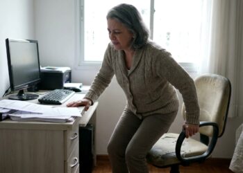 Profissional se levanta após permanecer muito tempo sentada no computador.