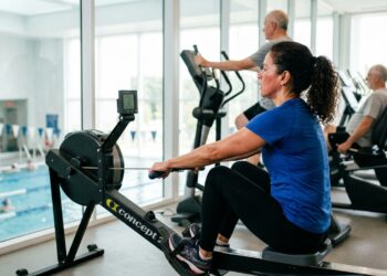 Mulher com mais de 50 anos faz exercício aeróbio no remo ergométrico em academia.