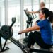 Mulher com mais de 50 anos faz exercício aeróbio no remo ergométrico em academia.
